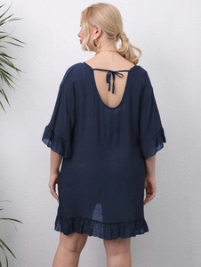 Detail of navy blue backless dress featuring ruffle edges and tie-back beach cover-up style