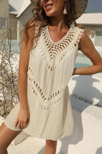 Close-up of beige crochet beach cover-up featuring V-neckline and fringe tassels