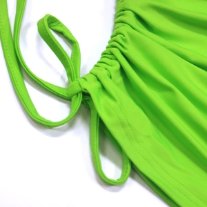 Macro detail of vibrant green ribbed crop top with adjustable drawstring ruched side