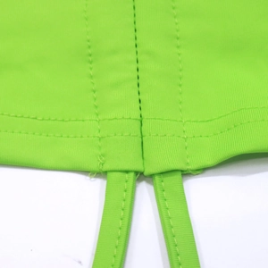 Detailed close-up of double-stitched seams and thin straps on neon green crop top