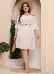 Detailed close-up of colorful tassel trim and intricate hollow crochet on a white dress