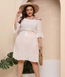 Detail of off-shoulder neckline with colorful pom-pom trim on a white plus size beach dress