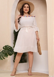 Detail of white off-shoulder beach dress with colorful pom-poms and lace crochet trim