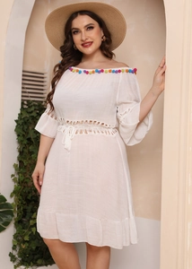 Close-up of bohemian white off-shoulder dress with colorful pompoms and hollow crochet lace