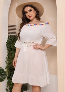 Detailed close-up of white off-shoulder beach dress with colorful pompoms and lace details