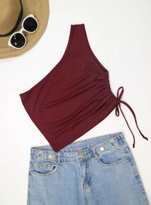 Flat lay of wine red one-shoulder crop top with drawstring ruching and summer accessories