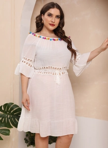 Detail of white plus size beach dress featuring colorful pom-poms and crochet hollow waist