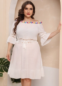 Detail of white boho beach cover-up with colorful pompoms and hollow crochet lace