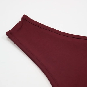 Detailed close-up of dark red crop top featuring neat stitching and smooth elastic fabric