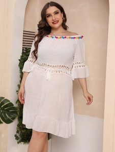 Close-up of colorful pom-pom neckline and intricate crochet details on white beach dress