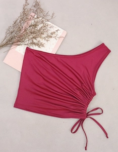 Detail of burgundy one-shoulder cropped top featuring side ruching and adjustable drawstrings