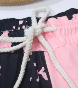 Détail de la taille élastique avec cordon de serrage blanc sur pantalon imprimé vache rose