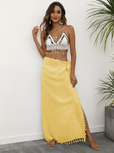 Detail of white and green crochet top with shell tassels and yellow wrap beach skirt