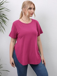 Detail view of the high side slit and curved hem on a rose red short sleeve top