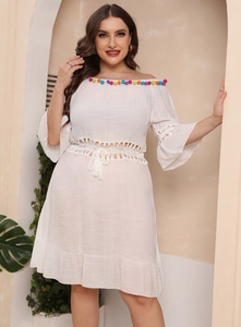 Detail of white off-shoulder beach dress with colorful pom-poms and crochet hollow sleeves