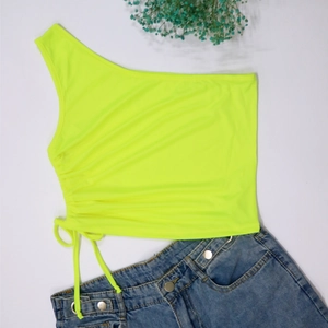 Detail view of neon yellow one-shoulder crop top with side drawstring ruching details