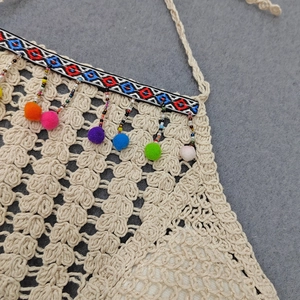 Detail of crochet bikini top with bohemian geometric tape and colorful pompom tassels