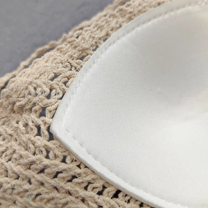 Detailed close-up of beige crochet knit bikini top with white stitched inner lining cups