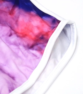 Gros plan sur un short en maille tie-dye aux couleurs violettes et rouges et bordure blanche