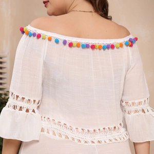 Detail view of white off-shoulder beach dress with colorful tassels and crochet lace trim