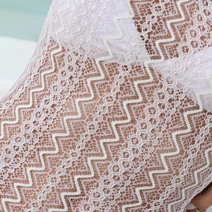 Macro shot of pale pink lace beach cover-up showing geometric wave crochet texture