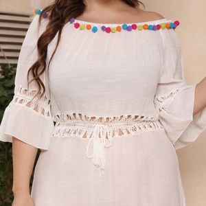 Detail of off-shoulder dress with colorful pom-poms, crochet lace, and tassel drawstring