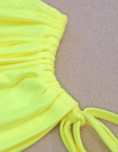 Detail of neon yellow drawstring fabric with elastic gathering and precise stitching