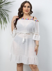 Detailed view of colorful tassel fringes and crochet lace trim on white beach coverup