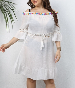 Detail of white off-shoulder beach dress with colorful pom-poms and crochet hollow patterns