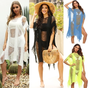 Macro shot of torn mesh texture and long tassel details on a sexy crochet beach cover-up