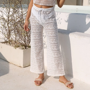 Dettaglio dei pantaloni a zampa in pizzo bianco con motivo zigzag e coulisse in vita