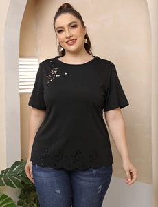Détail de fleurs découpées au laser et ourlet ondulé sur un t-shirt noir grande taille