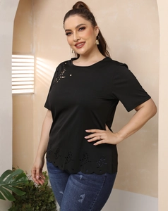 Détail de motif rose dévoré ajouré et ourlet ondulé sur un t-shirt noir grande taille