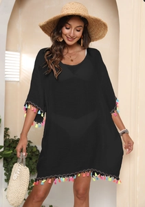 Detail shot of colorful fringe tassels on the hem of a black bohemian beach cover-up dress