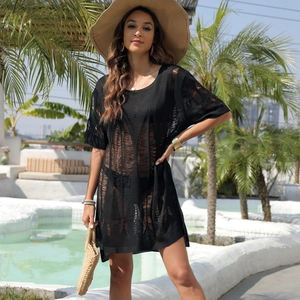 Close-up of black hollow-out knit beach cover-up with textured mesh detail poolside
