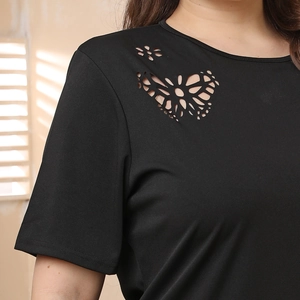 Detail of laser-cut butterfly and flower patterns on black short-sleeve A-line dress