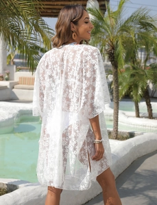 Detail of white floral lace beach cover-up with colorful embroidery on the neckline