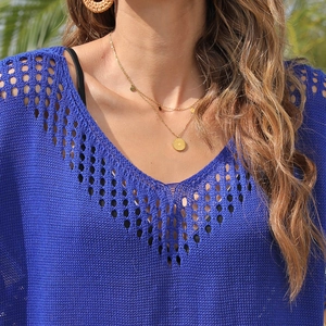 Close-up of royal blue V-neck hollow knit top with layered golden evil eye necklace