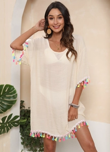 Detail of colorful tassel fringe on loose beige beach cover-up dress with V-neckline