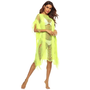 Detail of neon green crochet beach cover-up featuring open knit texture and long tassels