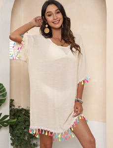 Close-up of beige beach cover-up with vibrant colorful tassel trim details
