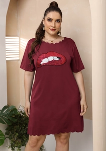 Détail de la broderie lèvres rouges et des bords festonnés sur la robe bordeaux