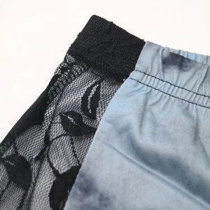 Détail macro du tissu tie-dye bleu avec empiècements en dentelle noire sur short