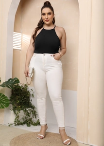 Detail van plus size haltertop en witte skinny jeans met hoge taille op het model