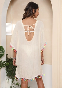 Detail of bohemian beige beach cover-up featuring colorful tassels and back tie design