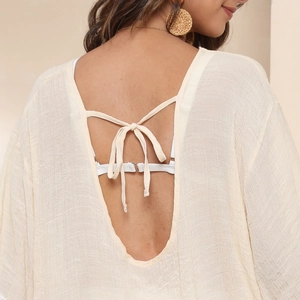 Close-up of the deep U-shaped backless design with tie detail on a beige beach cover-up