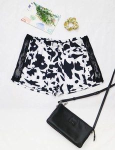 Vue à plat du short décontracté à motif vache avec dentelle noire et taille élastique