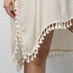 Gros plan d'une robe de plage beige avec des franges et une texture tissée chic