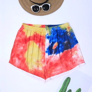 Summer tie-dye beach shorts with elastic waist and white piping trim on a beach set