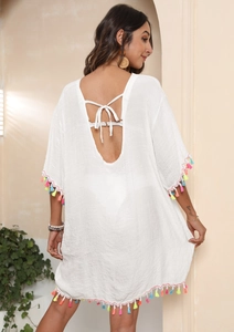 Detail of white beach cover-up featuring vibrant multi-colored fringe and tie-back V-neck